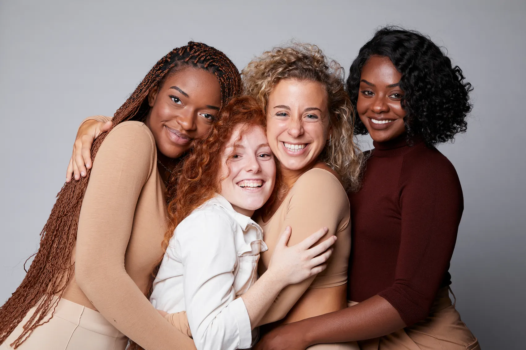 A diverse group of moms from the Magenta Momz community holding each other and smiling
